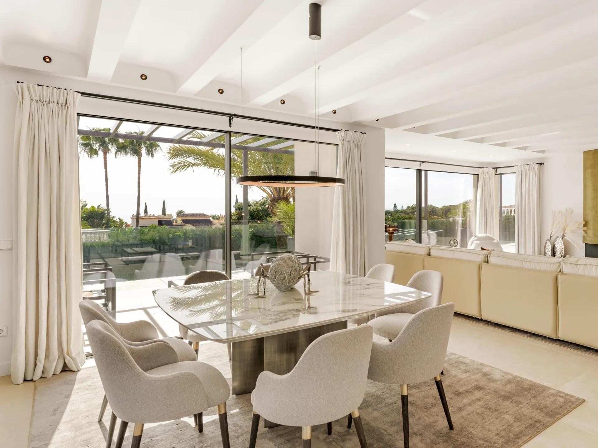 Bright living and dining room opening onto a terrace with palms