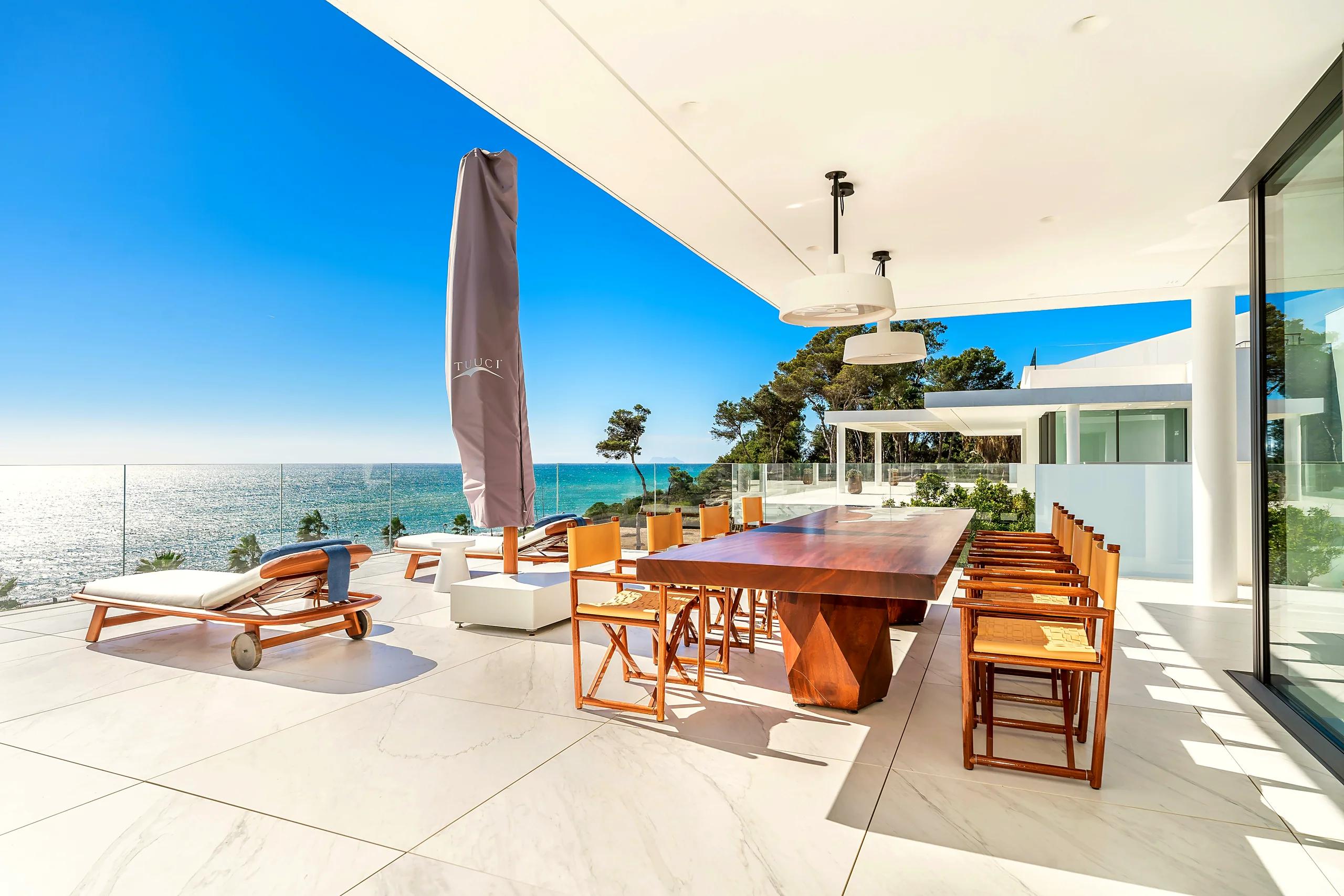 Sunny terrace of a modern villa with a dining table right above the sea