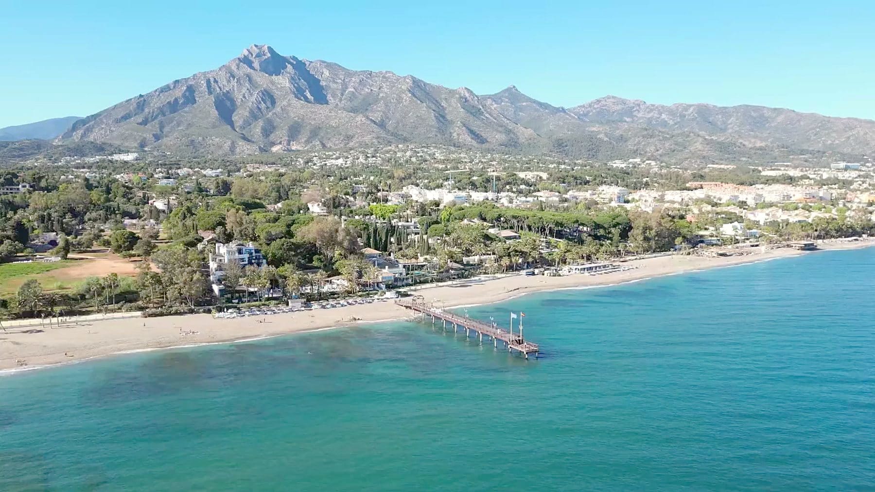 The beach and pier in Marbella beneath La Concha mountain