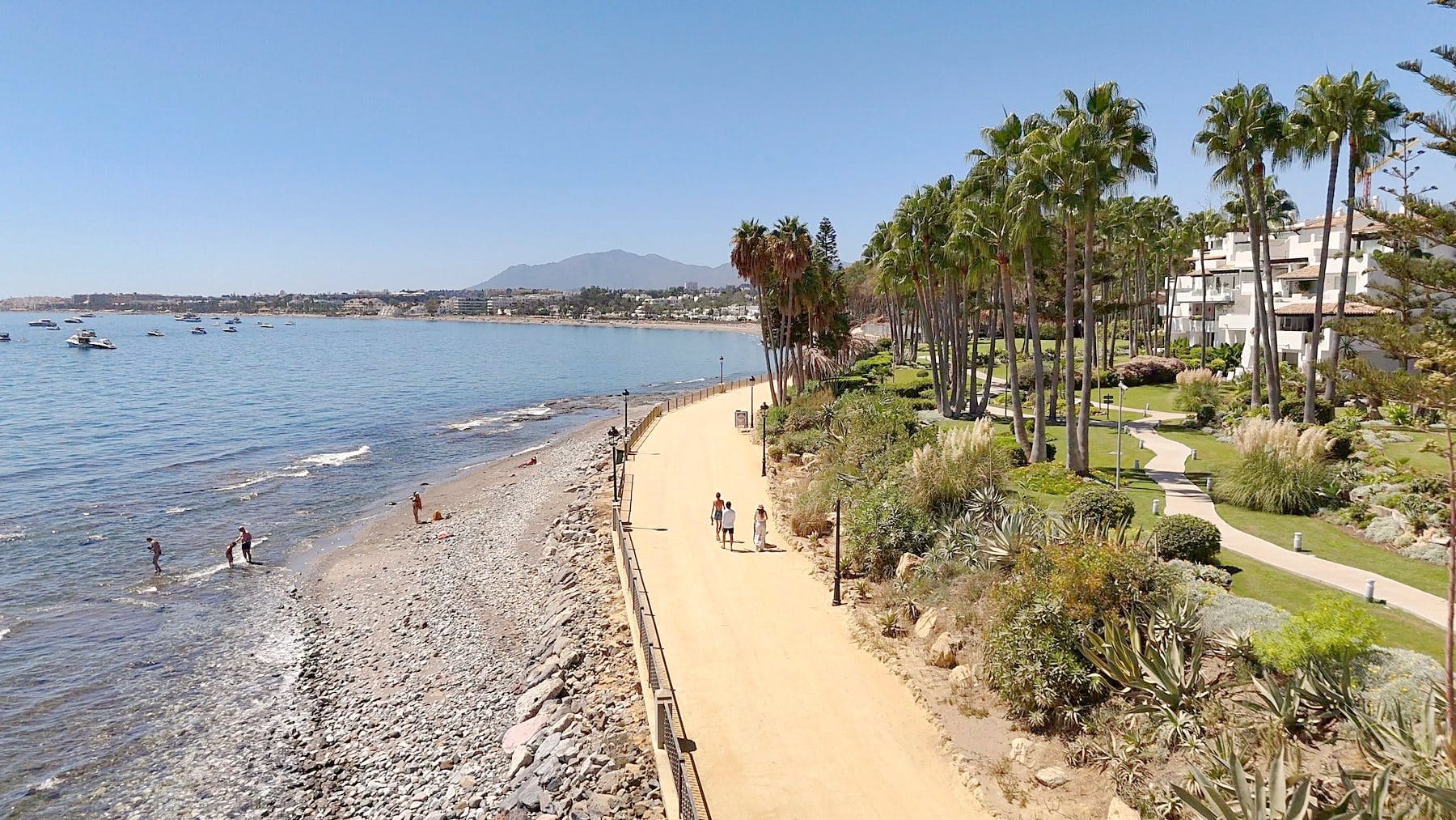 The seafront promenade in Marbella with gardens and palm trees, La Concha mountain in the distance