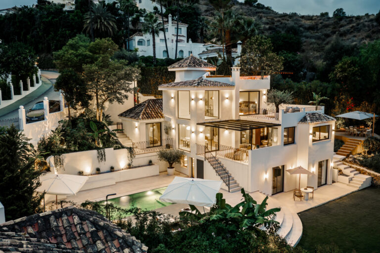 Luxurious multi-level villa with illuminated exterior at twilight, showcasing modern architecture, a private pool, landscaped garden, and outdoor living spaces.